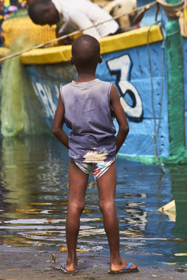 Boy watching fishing boat come into West Point – Monrovia, Liberia